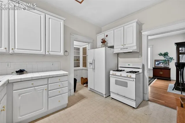 a kitchen with white cabinets and white appliances