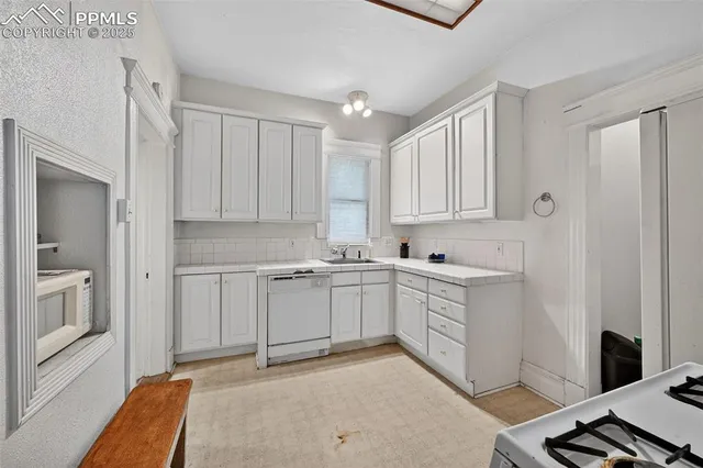 a kitchen with white cabinets and sink