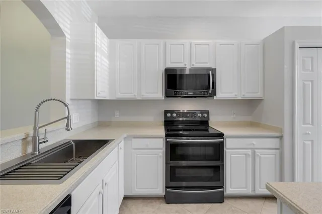 a kitchen with white cabinets and stainless steel appliances