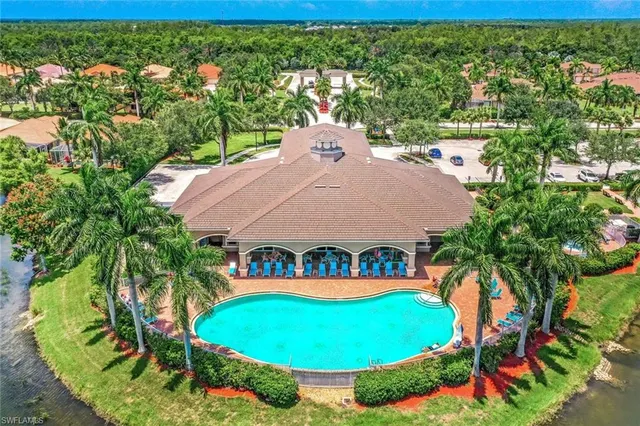 an aerial view of a house with swimming pool and large trees