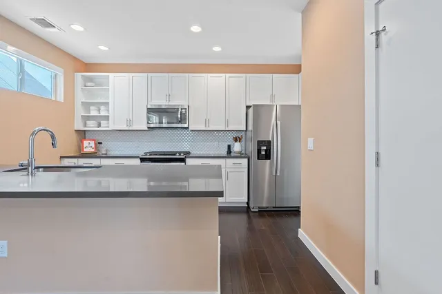 a kitchen with stainless steel appliances granite countertop a sink a stove and a refrigerator