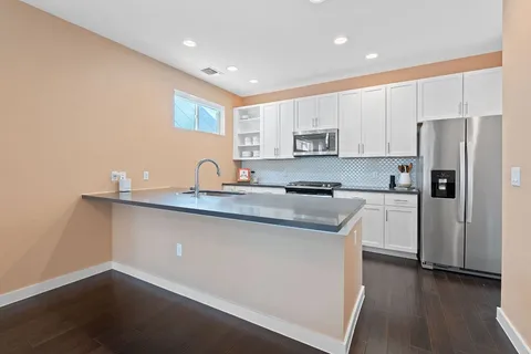 a kitchen with kitchen island granite countertop a sink cabinets and stainless steel appliances
