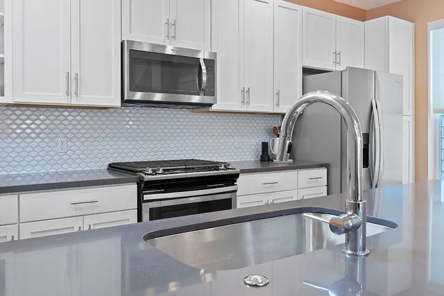 a kitchen with granite countertop a stove and a microwave with cabinets