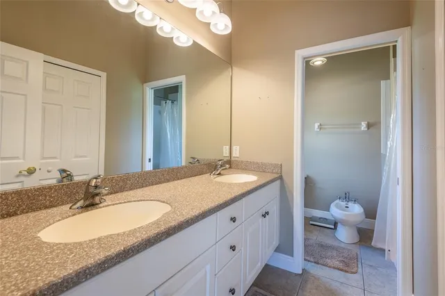 a bathroom with a granite countertop double vanity sink a mirror and a toilet