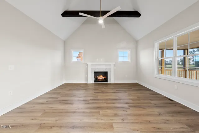 a view of an empty room with wooden floor fireplace and a window