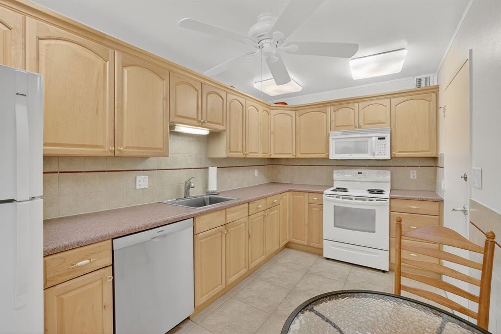 405 North Ocean Boulevard, Unit 1027 Pompano Beach, FL 33062 - Photo 7 of 57 a kitchen with white cabinets stainless steel appliances and sink