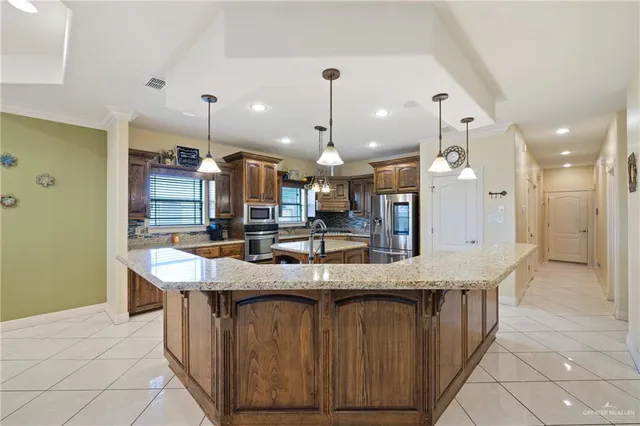 a large kitchen with a large counter top a sink stainless steel appliances and cabinets