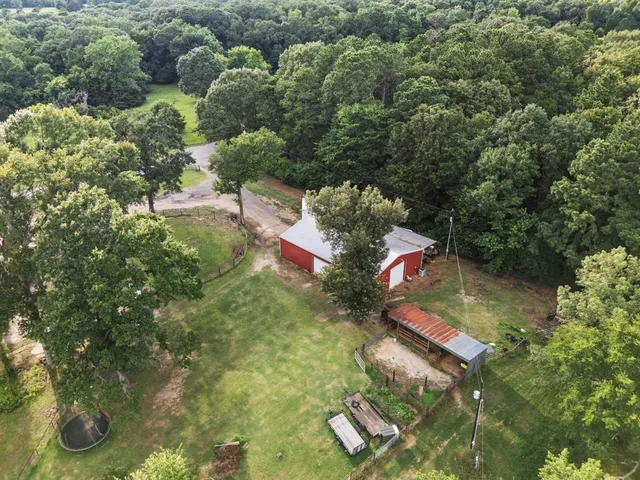 an aerial view of residential house with outdoor space and trees all around