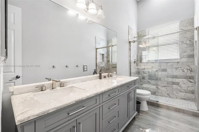 a bathroom with a granite countertop sink a toilet and a mirror