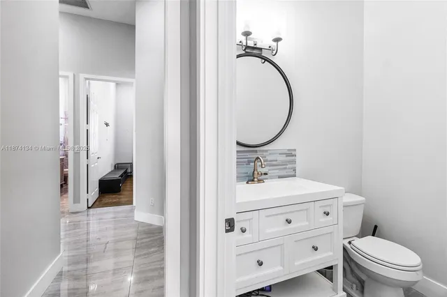 a bathroom with a toilet sink vanity and mirror