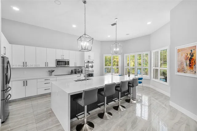 a large kitchen with cabinets chairs and white appliances