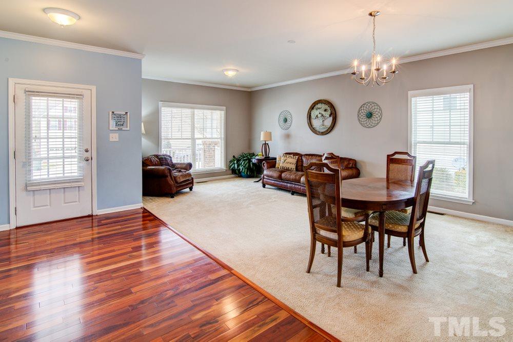 874 Seastone Street Raleigh, NC 27603 - Photo 3 of 30 a dining room with wooden floor a chandelier a wooden table and chairs