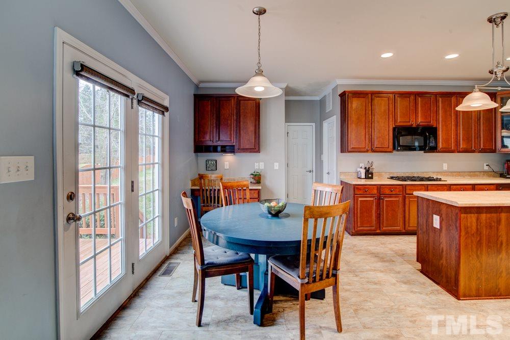 874 Seastone Street Raleigh, NC 27603 - Photo 7 of 30 a kitchen with stainless steel appliances granite countertop a stove top oven a sink a refrigerator with a dining table and chairs