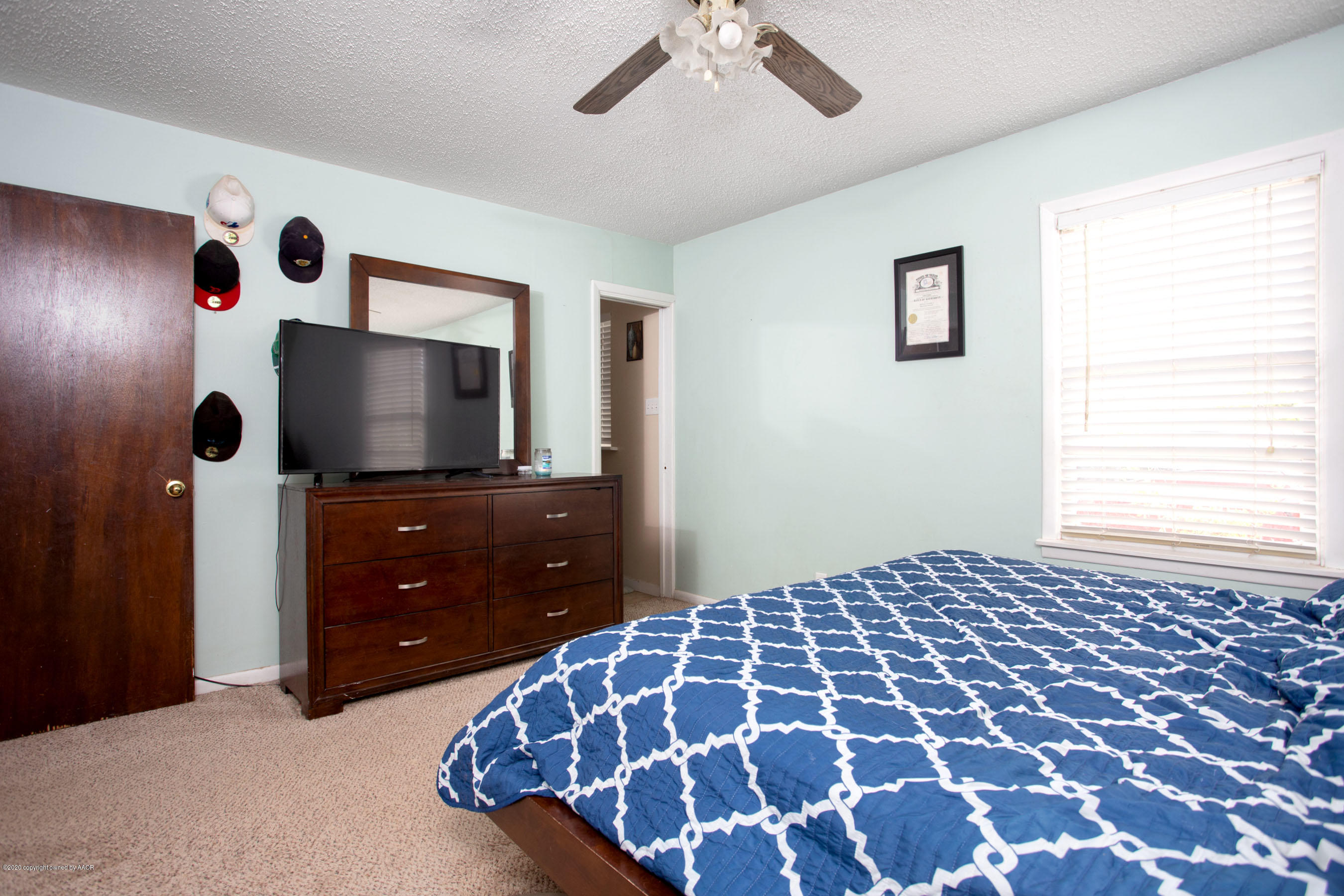 4712 South Milam Street Amarillo, TX 79110 - Photo 12 of 22 a bedroom with a bed and a flat tv screen on dresser