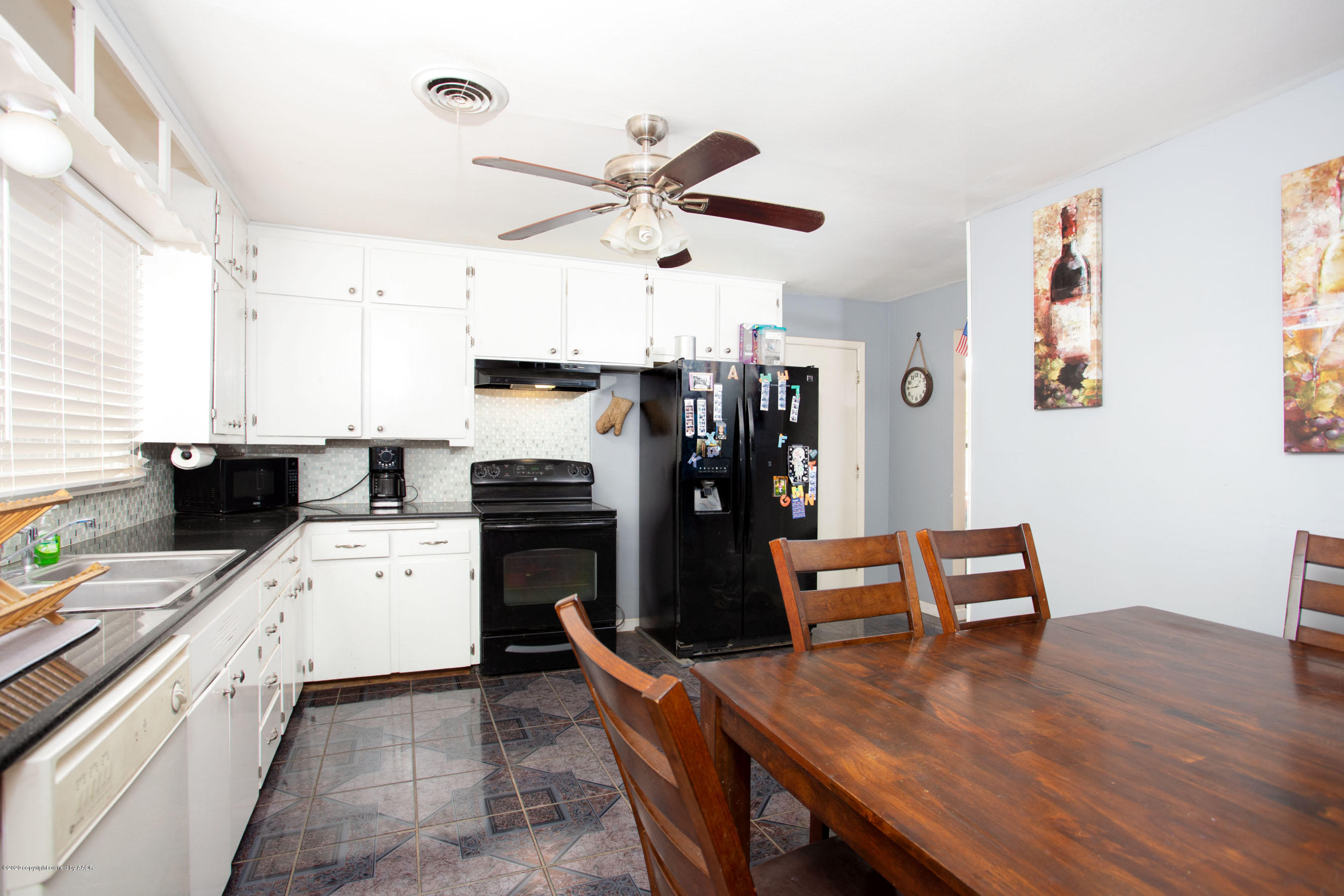 4712 South Milam Street Amarillo, TX 79110 - Photo 4 of 22 a kitchen with a refrigerator a stove top oven a dining table and chairs with wooden floor