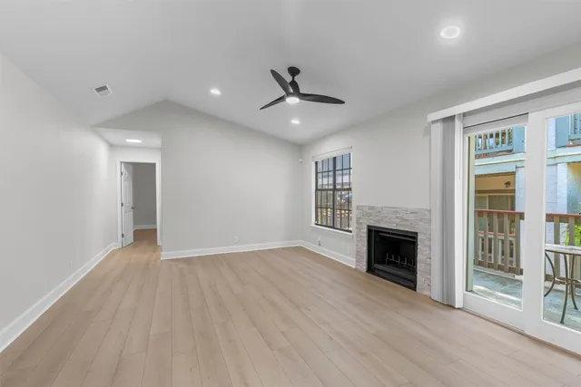 an empty room with fireplace wooden floor and windows