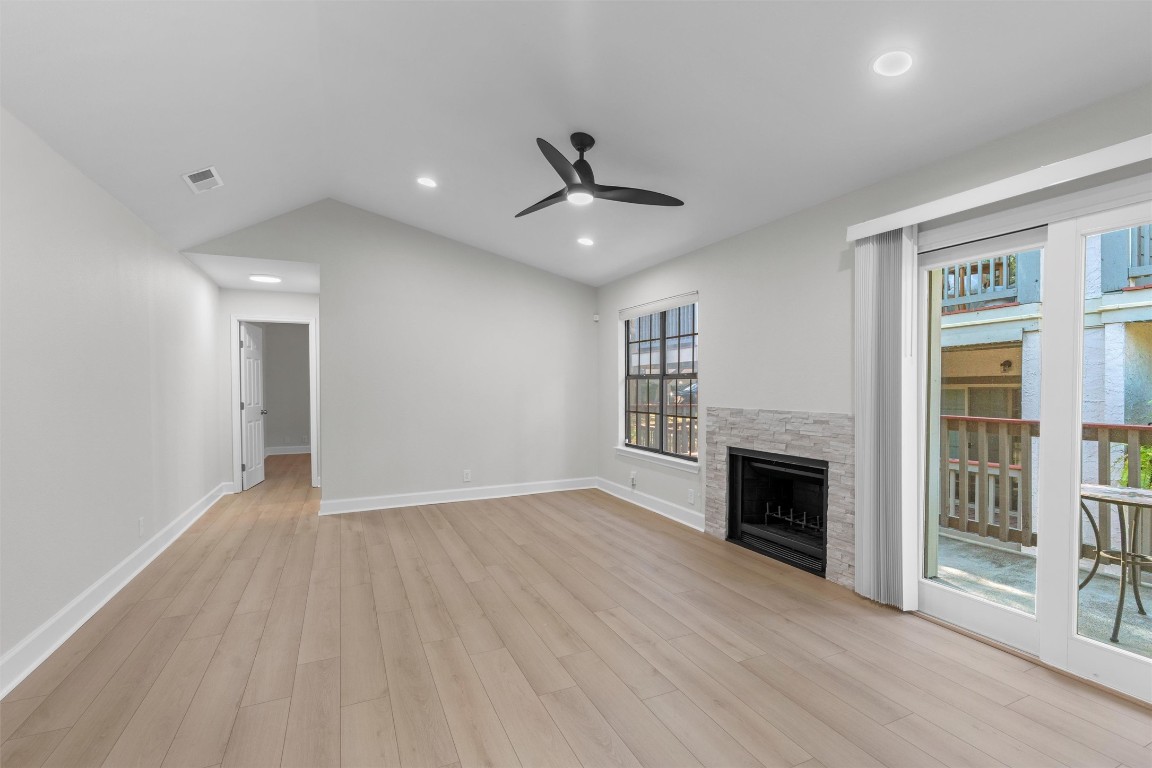 an empty room with fireplace wooden floor and windows