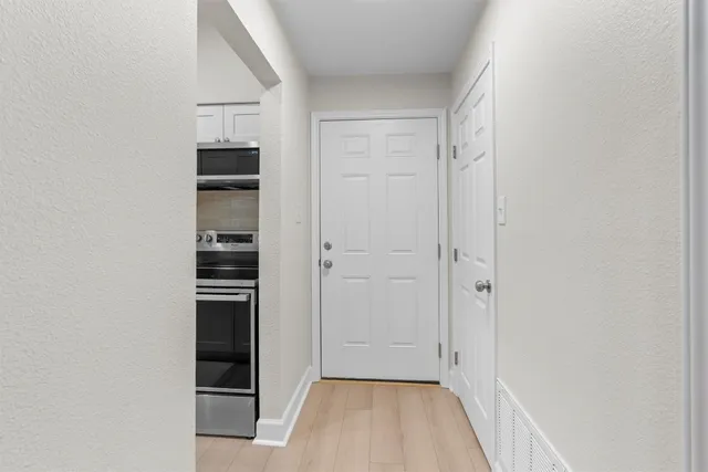 a view of empty room with wooden floor and kitchen