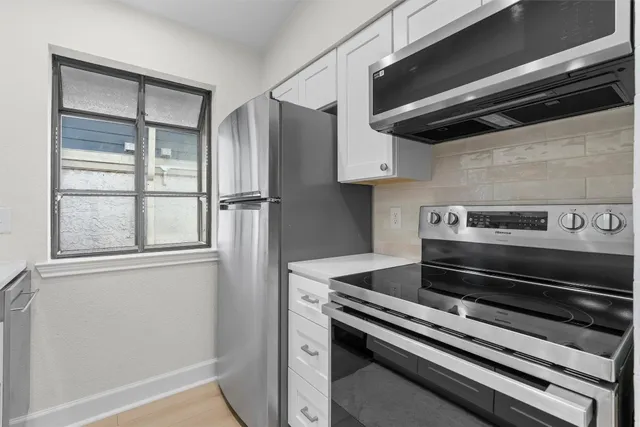 a kitchen with granite countertop white cabinets and stainless steel appliances