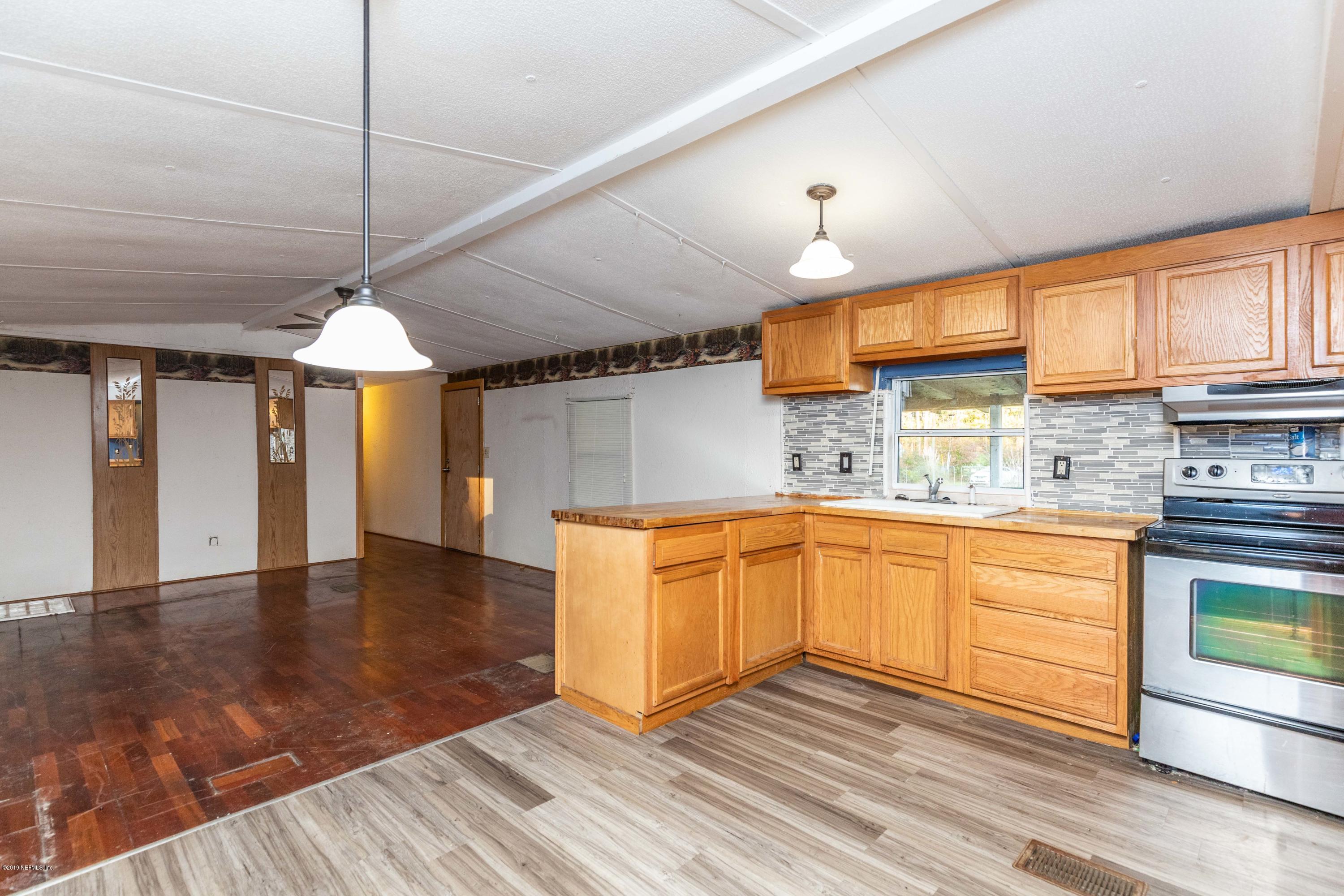 7840 Old Middleburg Road South Jacksonville, FL 32222 - Photo 30 of 46 a kitchen with granite countertop wooden floors and white cabinets