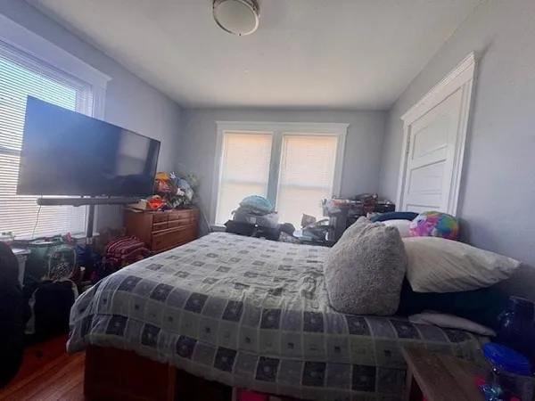 a bed sitting in a bedroom next to a window with a flat screen tv and dresser