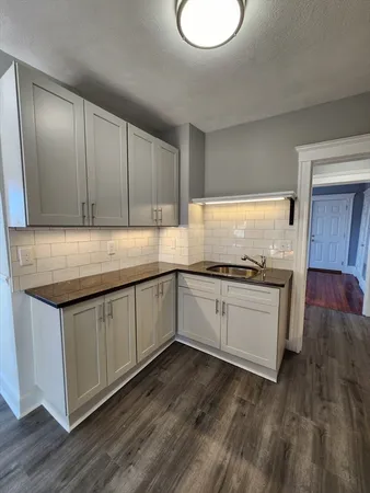a kitchen with granite countertop wooden cabinets a sink and dishwasher with wooden floor