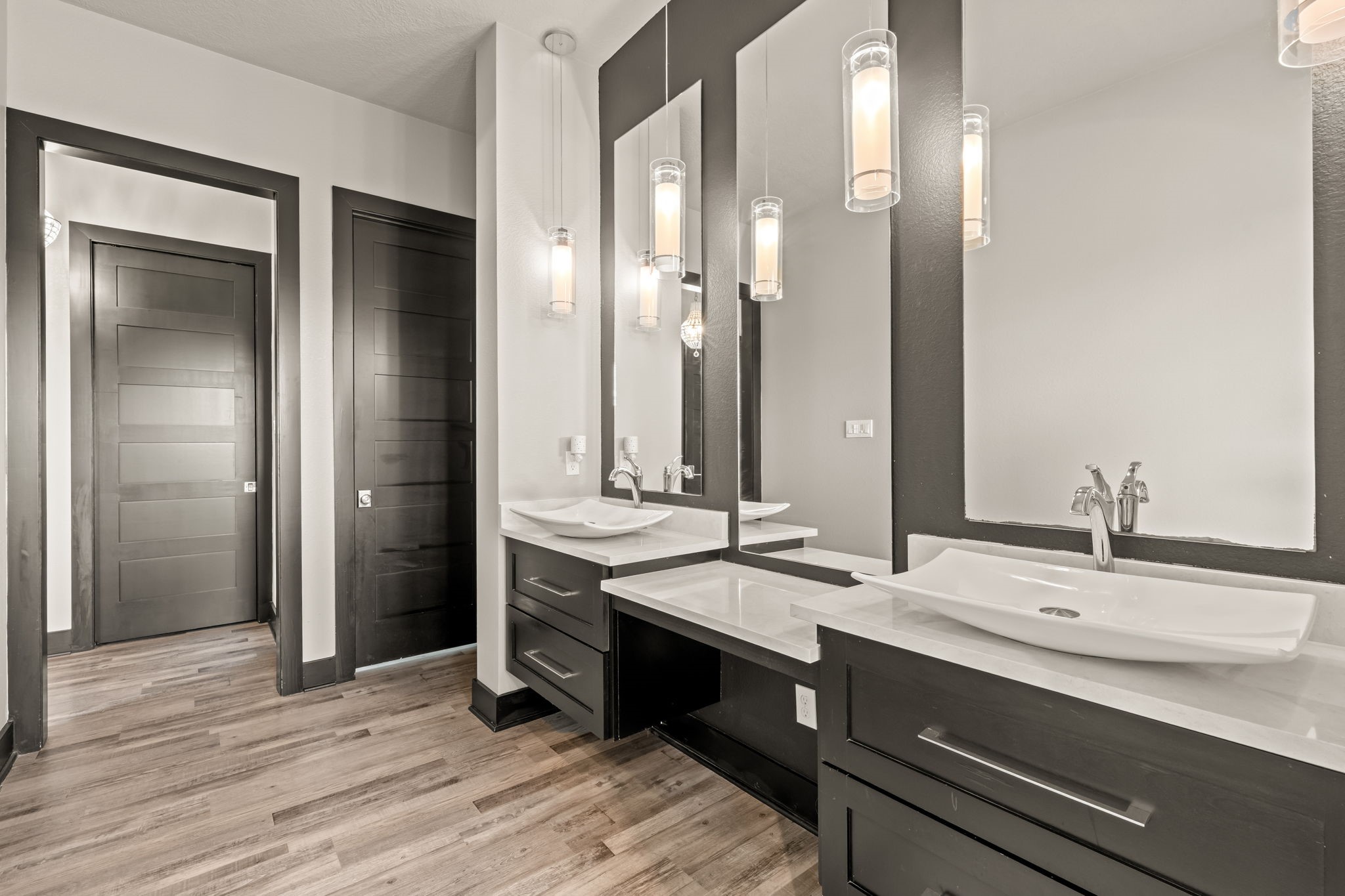 2856 Wolcek Road Crosby, TX 77532 - Photo 19 of 48 This modern bathroom features sleek dark cabinetry with dual vessel sinks, large mirrors, and elegant pendant lighting. The light wood flooring complements the contemporary design, creating a stylish and functional space.