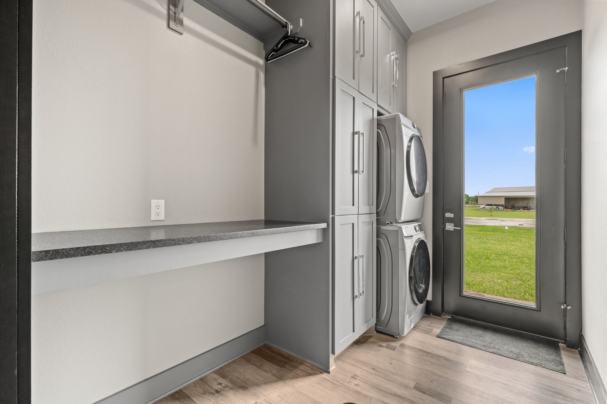 2856 Wolcek Road Crosby, TX 77532 - Photo 26 of 48 Modern laundry room with stacked washer and dryer, ample cabinetry, and a built-in countertop. A large glass door provides natural light and outdoor access.