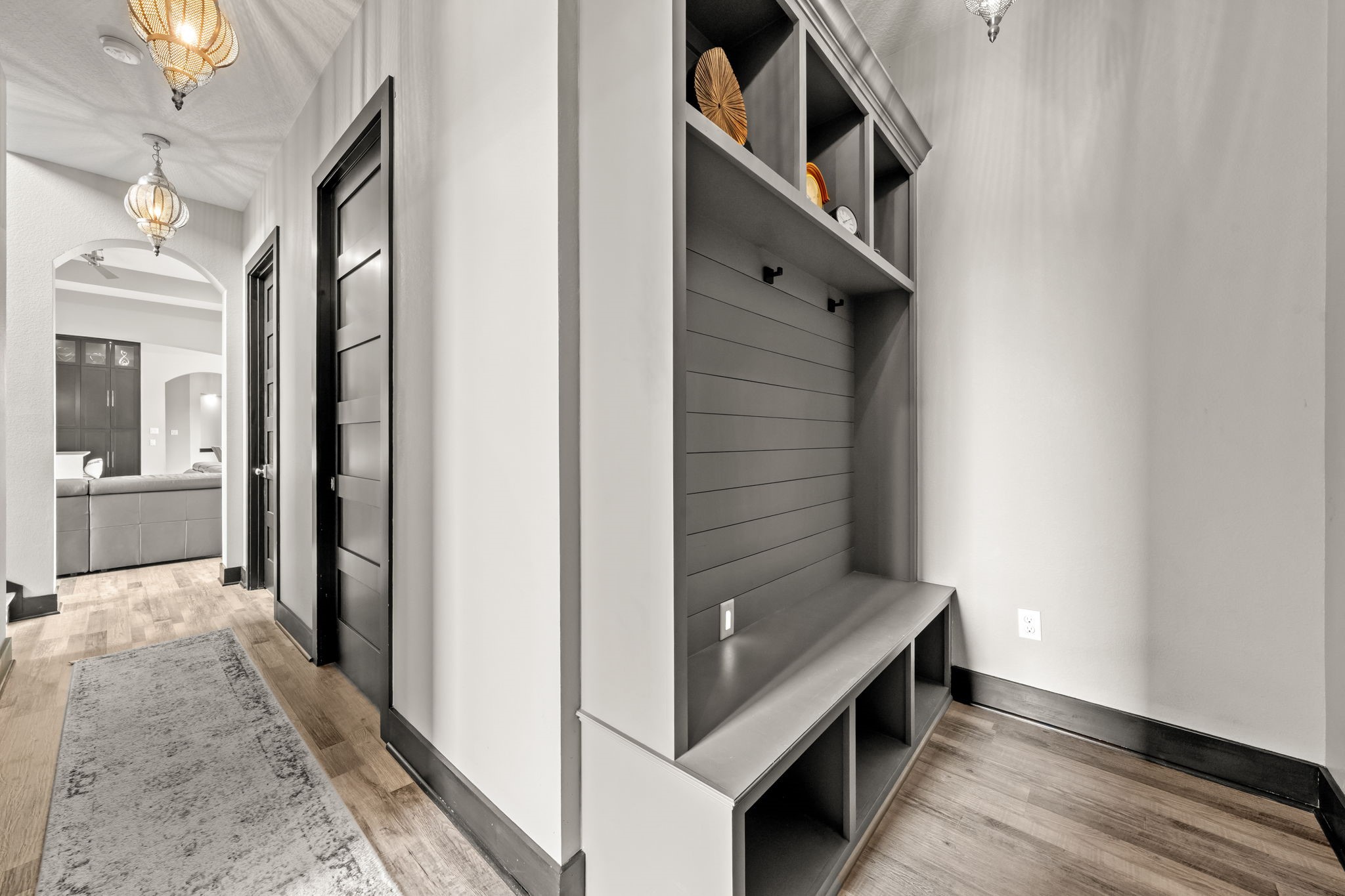 2856 Wolcek Road Crosby, TX 77532 - Photo 27 of 48 This hallway mudroom features sleek dark wood doors, elegant pendant lighting, and a functional built-in storage bench with shelves. The light wood flooring and neutral walls create a warm, inviting atmosphere, leading into a spacious living area with an oversized hallway that suits any ADA needs and an elevator-ready closet.