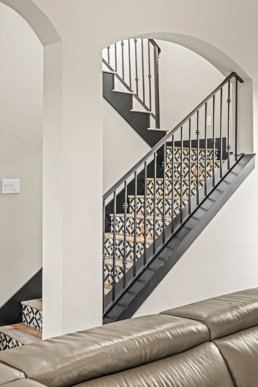 2856 Wolcek Road Crosby, TX 77532 - Photo 29 of 48 This photo showcases a stylish staircase with decorative tile risers and a sleek black metal railing, framed by an elegant archway, creating a modern yet inviting focal point in the home.