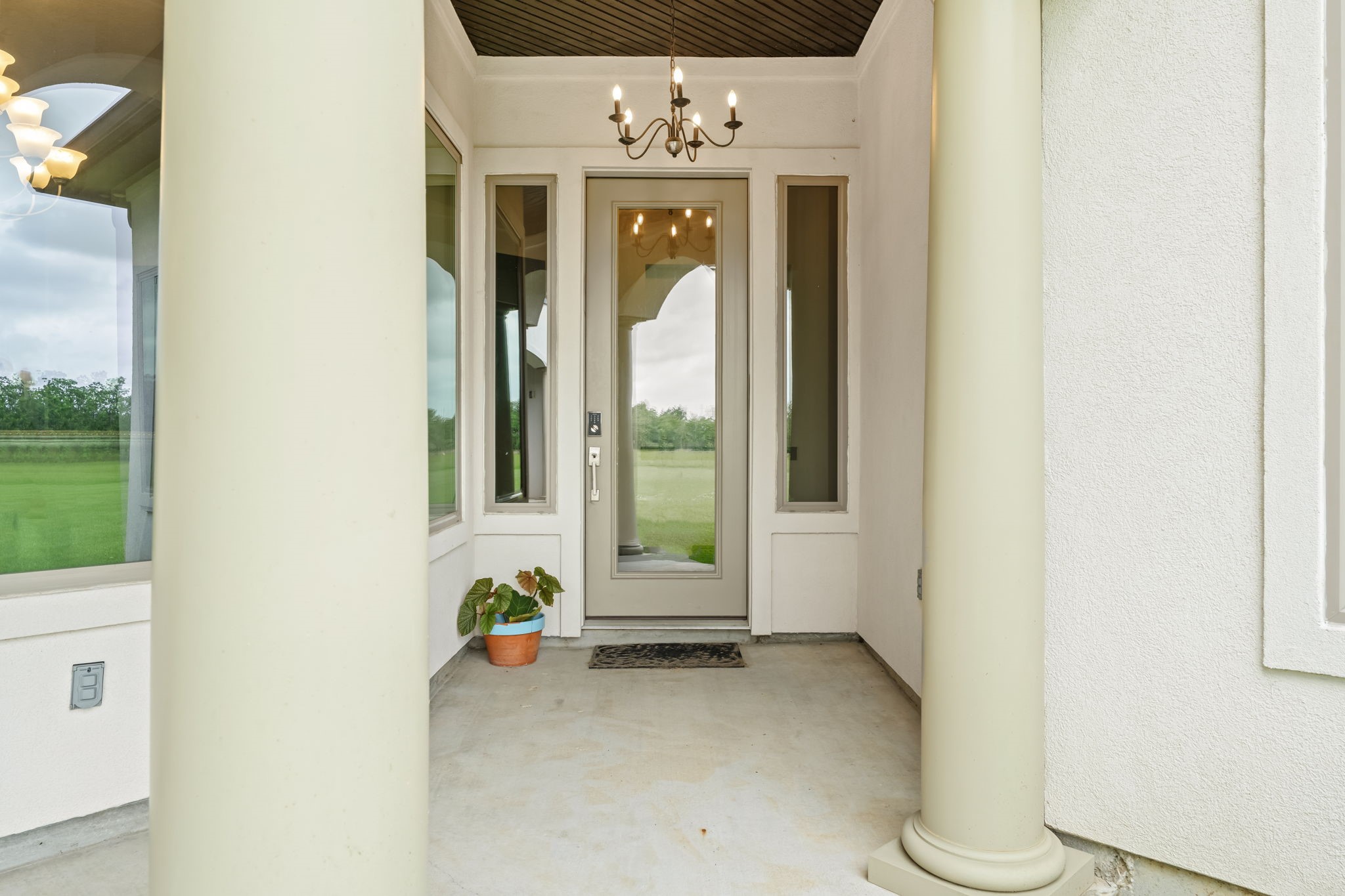 2856 Wolcek Road Crosby, TX 77532 - Photo 9 of 48 The inviting entryway features a glass-paneled door flanked by tall windows, framed by elegant columns. A chandelier overhead provides sophisticated ambiance.
