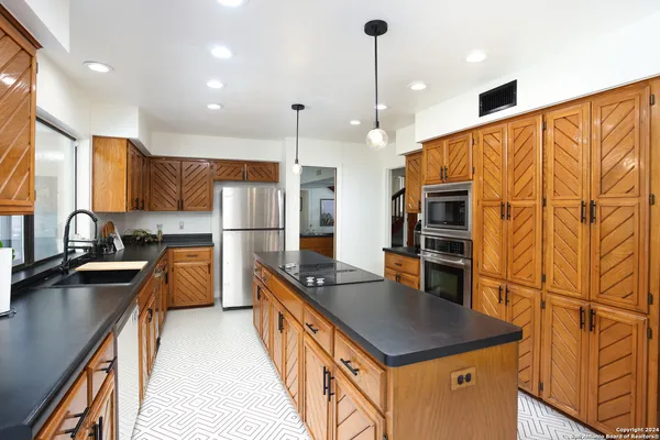 a kitchen with stainless steel appliances granite countertop a sink a stove and a refrigerator