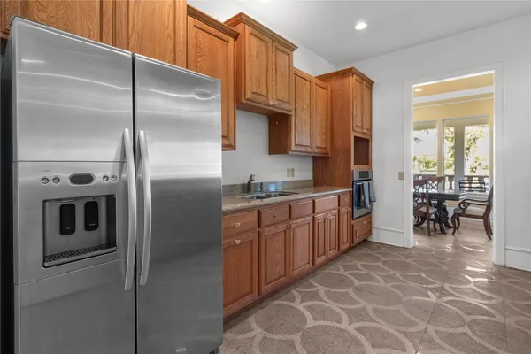 a kitchen with stainless steel appliances granite countertop a refrigerator a oven a sink with island and chairs