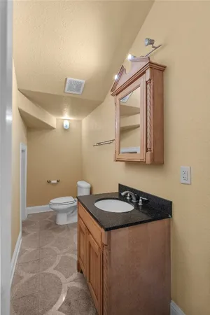 a bathroom with a granite countertop sink a toilet a mirror and vanity
