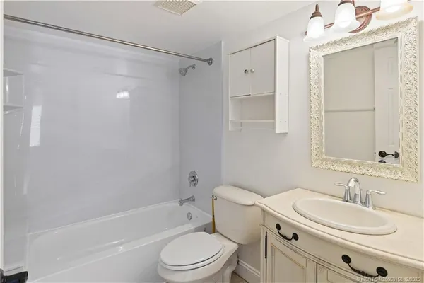 an empty room with a chandelier fan and windows