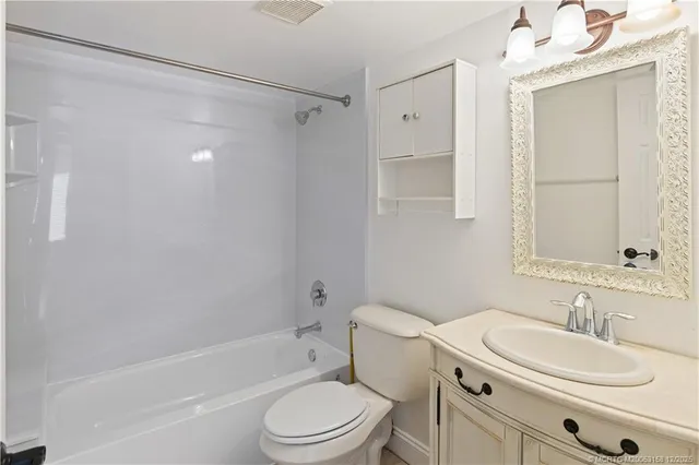 an empty room with a chandelier fan and windows