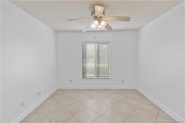 a view of an empty room and chandelier fan