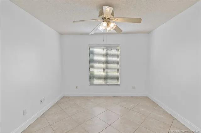 a view of an empty room and chandelier fan