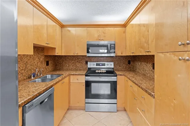a kitchen with stainless steel appliances granite countertop a refrigerator and a sink