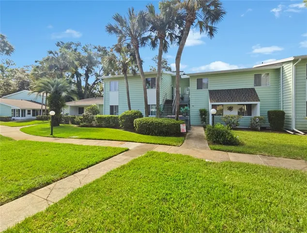 a view of a house with a big yard and palm trees