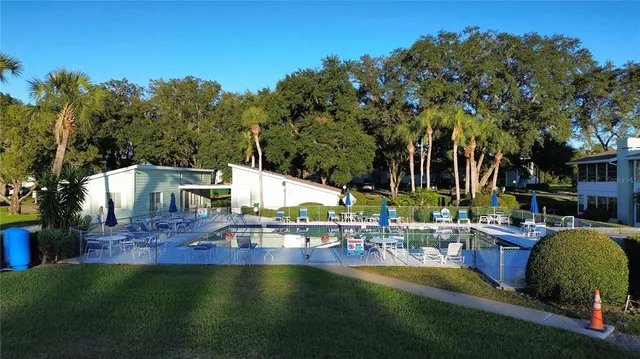 a view of a swimming pool with outdoor seating and a tree in the background