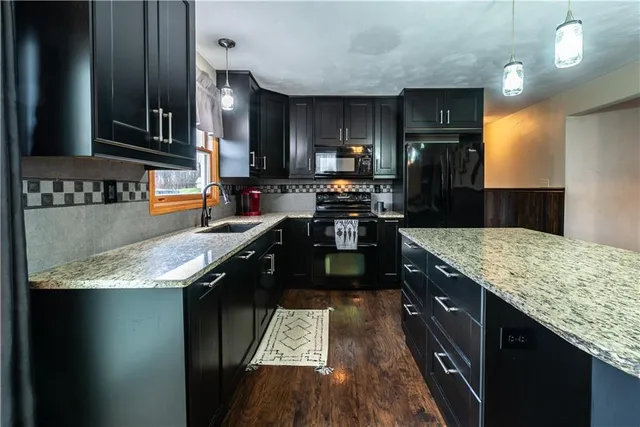 a kitchen with granite countertop a sink a counter top space stainless steel appliances and cabinets