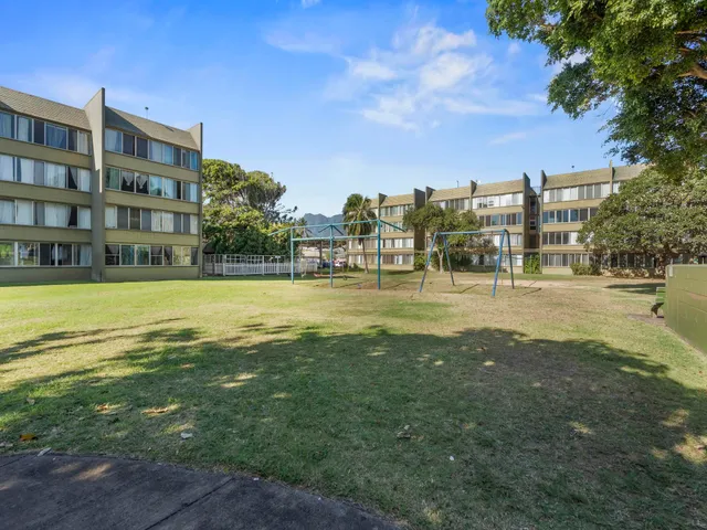 a view of a building with a big yard and large trees