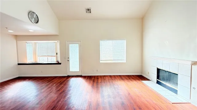 an empty room with wooden floor a fireplace and windows