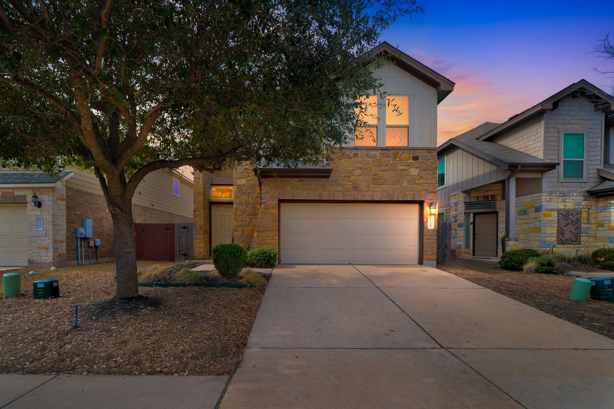 Inviting curb appeal with stone and stucco accents, mature landscaping, and an attached two-car garage in Preston Village.