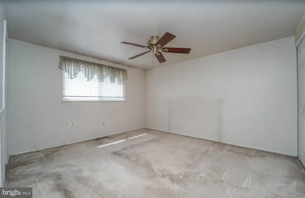 an empty room with a window and a fan