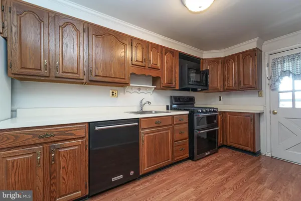 a kitchen with stainless steel appliances granite countertop wooden cabinets a sink and dishwasher with wooden floor