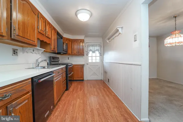 a kitchen with granite countertop wooden floors stainless steel appliances a sink and a window