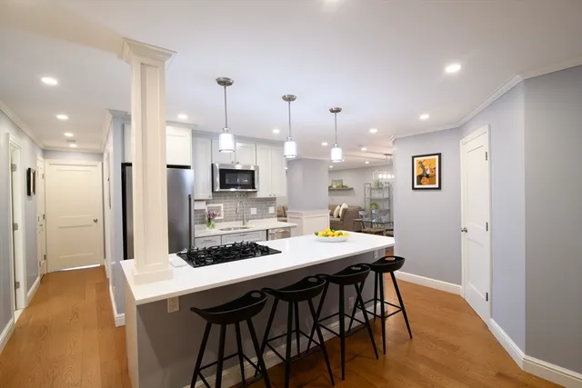 a kitchen with stainless steel appliances kitchen island granite countertop a table chairs and a refrigerator