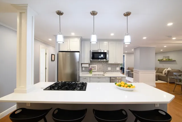 a kitchen with stainless steel appliances a dining table chairs and white cabinets